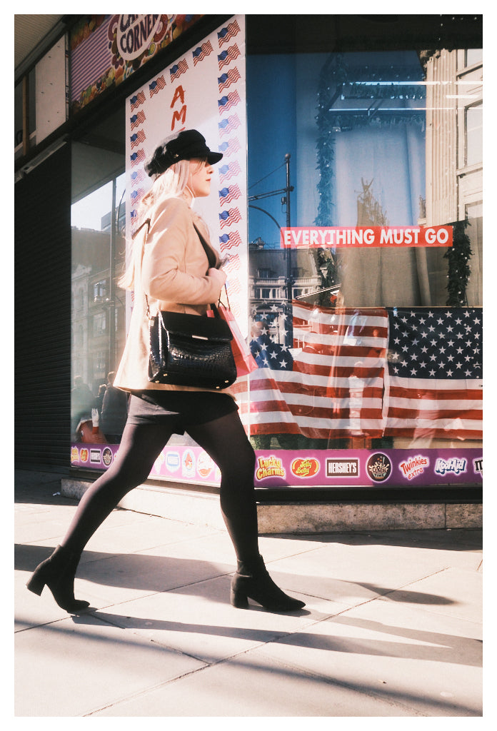 An elegant young woman walks past an "American-style" candy store in Oxford street, Westminster, London, United Kingdom